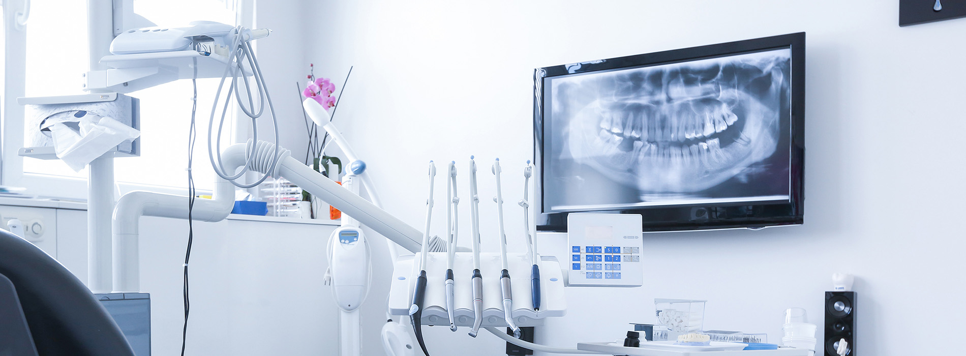 The image shows a modern dental clinic interior with various pieces of equipment, including a dental chair and an X-ray machine.