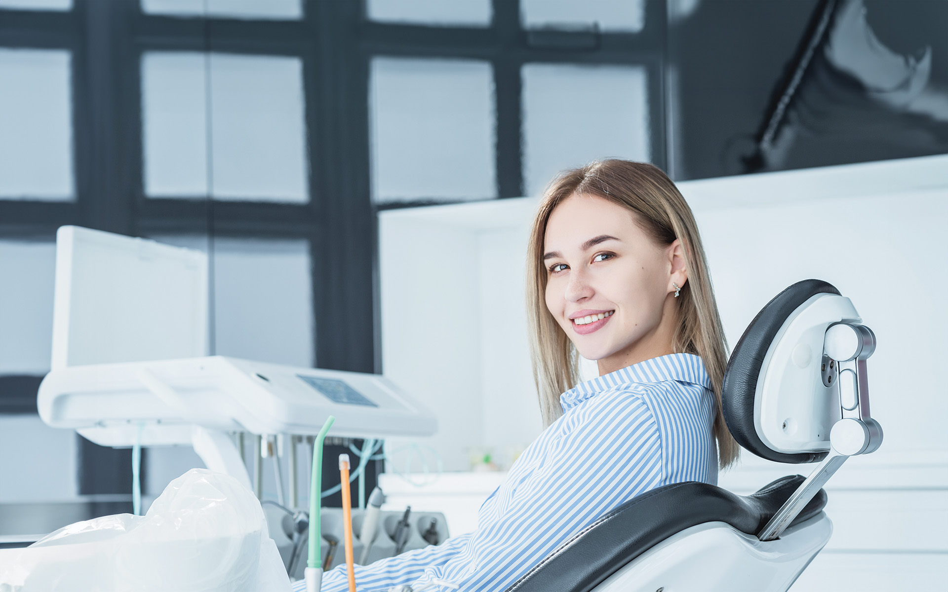 A modern dental practice with a blue and white chair, a dental treatment table, and medical equipment.